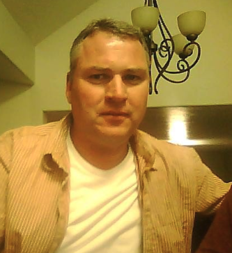 Head-and-shoulders photo image of Mike Marsh, wearing corduroy shirt over a white t-shirt. Male image with serious facial expression.